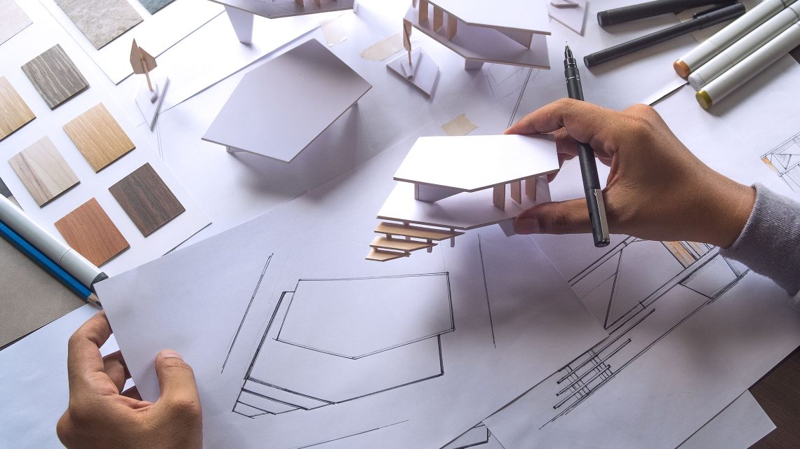 Arquiteto a comparar esboço desenhado em papel com modelo em baixa escala